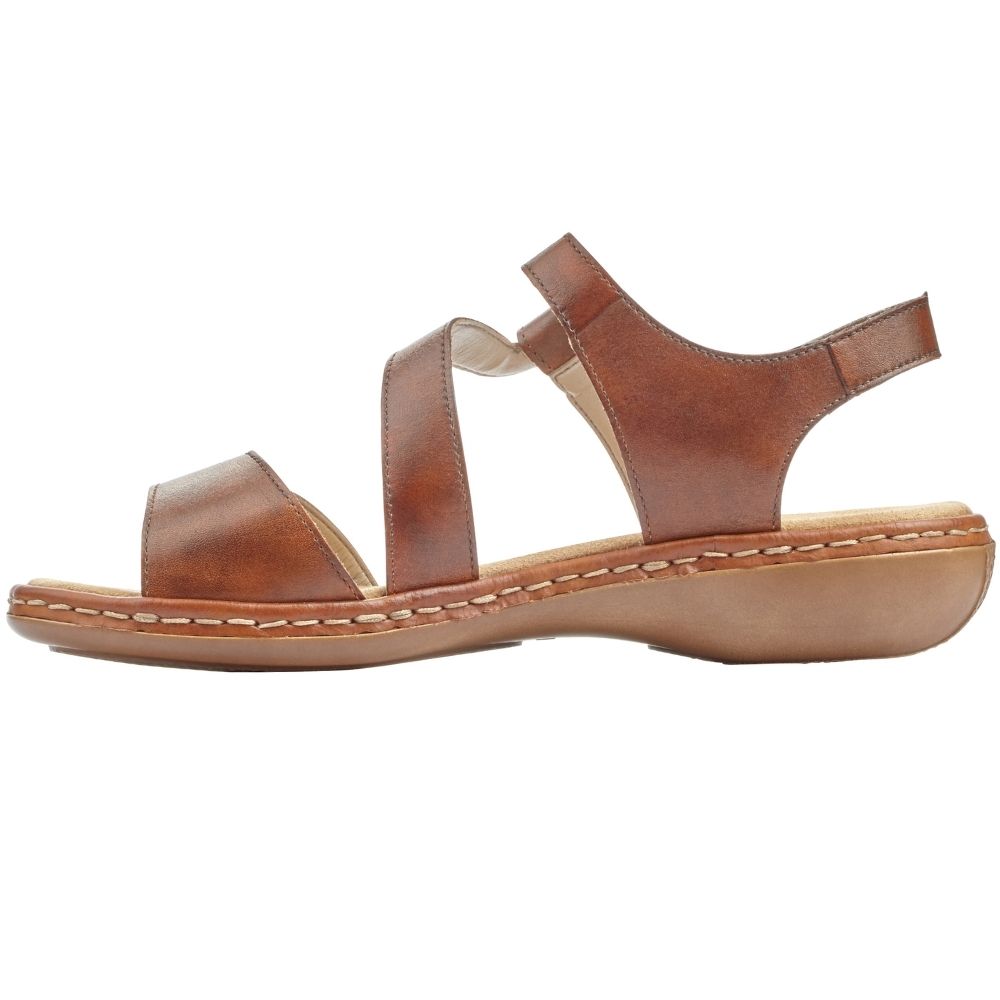 A tan leather flat sandal with a low wedge sole, featuring two adjustable straps and a heel strap, shown in a side profile on a white background.