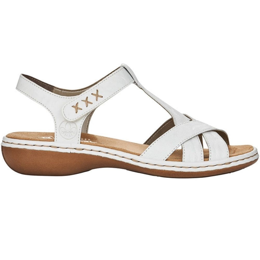 A white leather T-strap sandal with a brown sole, featuring decorative stitched details on the ankle strap and a light tan insole.