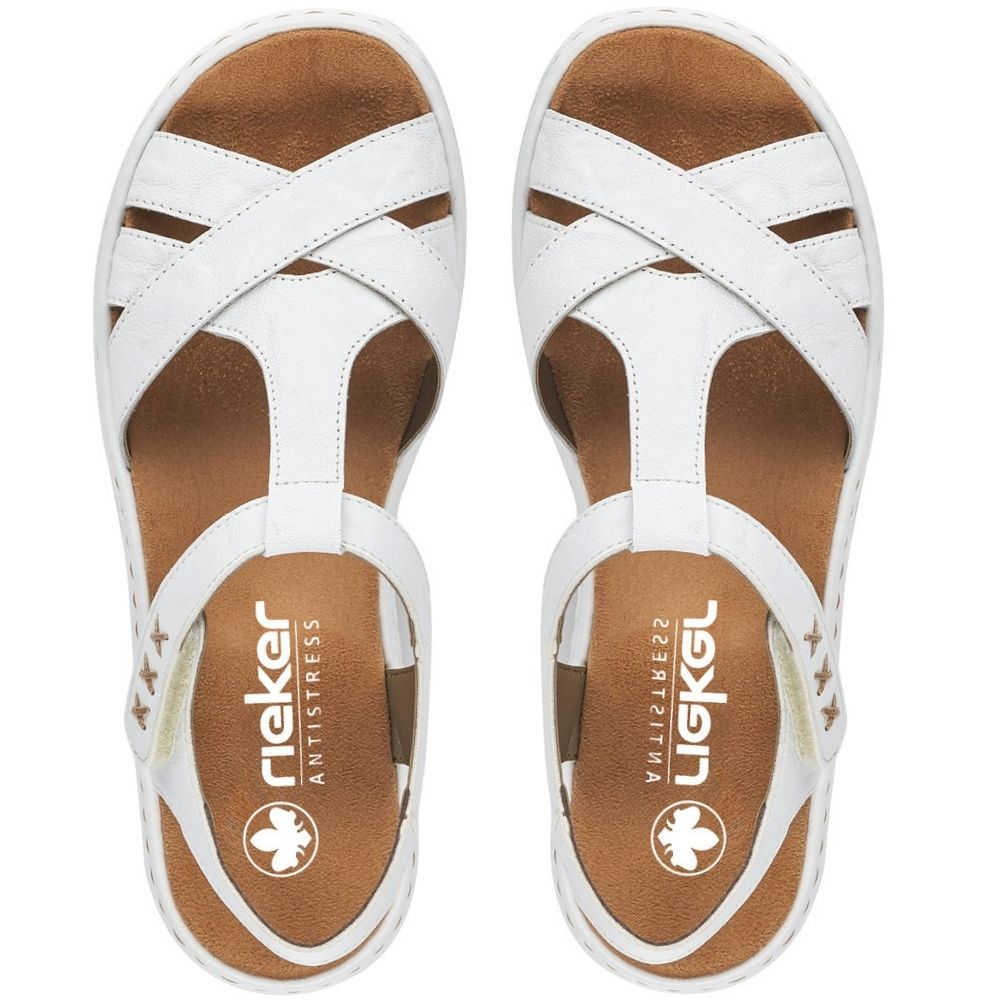 A pair of white leather cross-strap sandals with brown insoles, shown from a top-down view on a white background. The brand name 'RIEKER' is visible on the insole.
