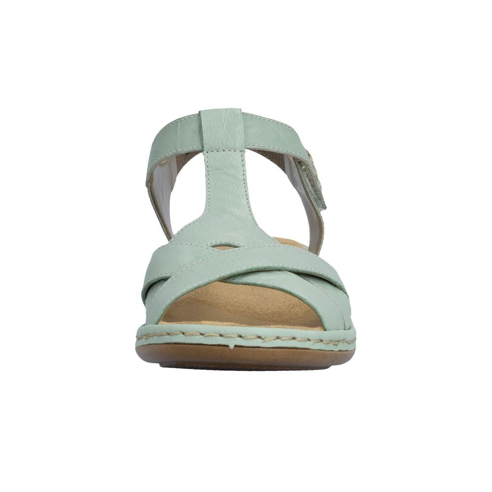 A light sage green T-strap sandal with a tan footbed and a light brown sole, shown from a front-facing perspective on a white background.