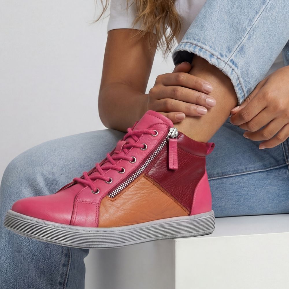 Person wearing a pink, orange and red high-top sneaker boot on a white background