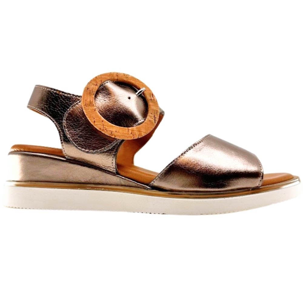 A metallic bronze leather wedge sandal with a wooden circular buckle detail on the strap, shown in a side profile against a white background.