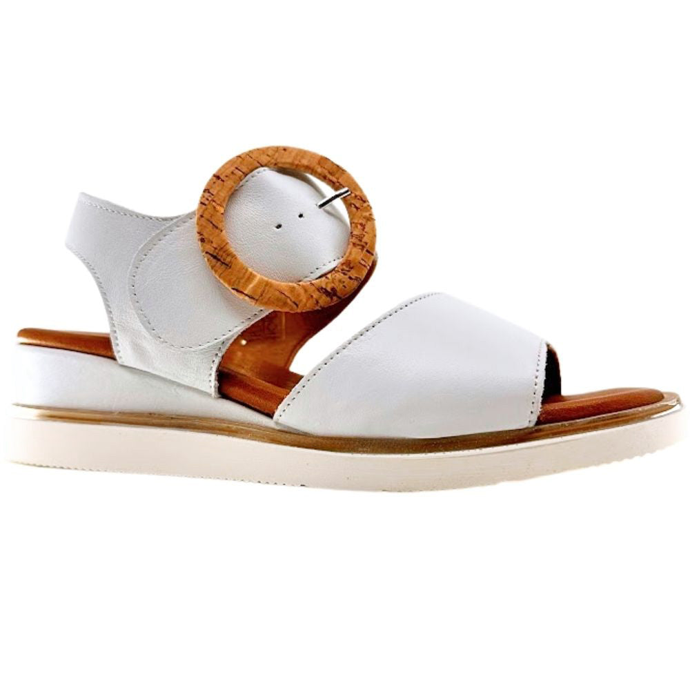 A white leather wedge sandal with an ankle strap, a wooden circular buckle, and a light beige sole, shown from a side profile on a white background.