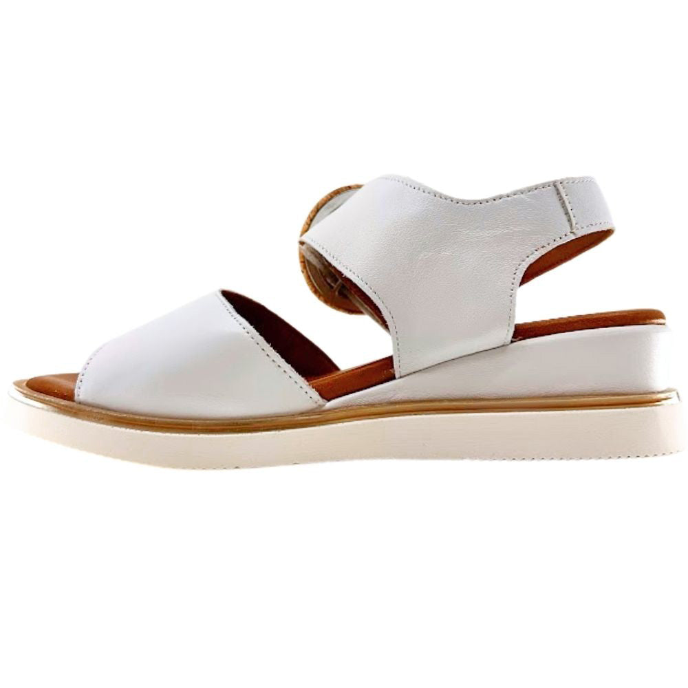 A white leather wedge sandal with an ankle strap and a light beige sole, shown from a side profile on a white background.