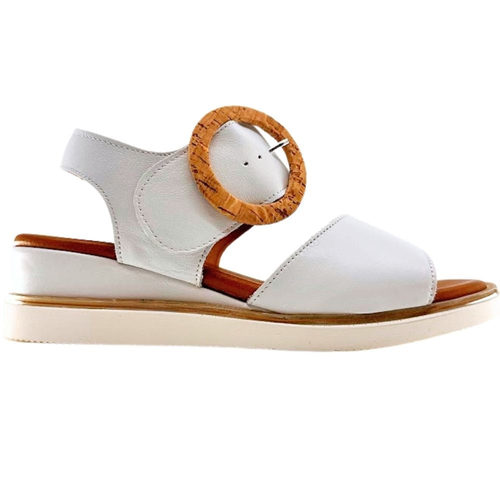 A white leather wedge sandal with an ankle strap, a wooden circular buckle, and a light beige sole, shown from a side profile on a white background.