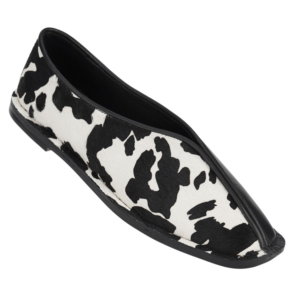 Black and white cow print flat shoe on a white background
