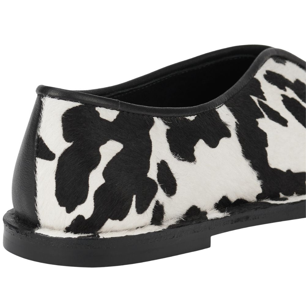 Black and white cow print flat shoe on a white background