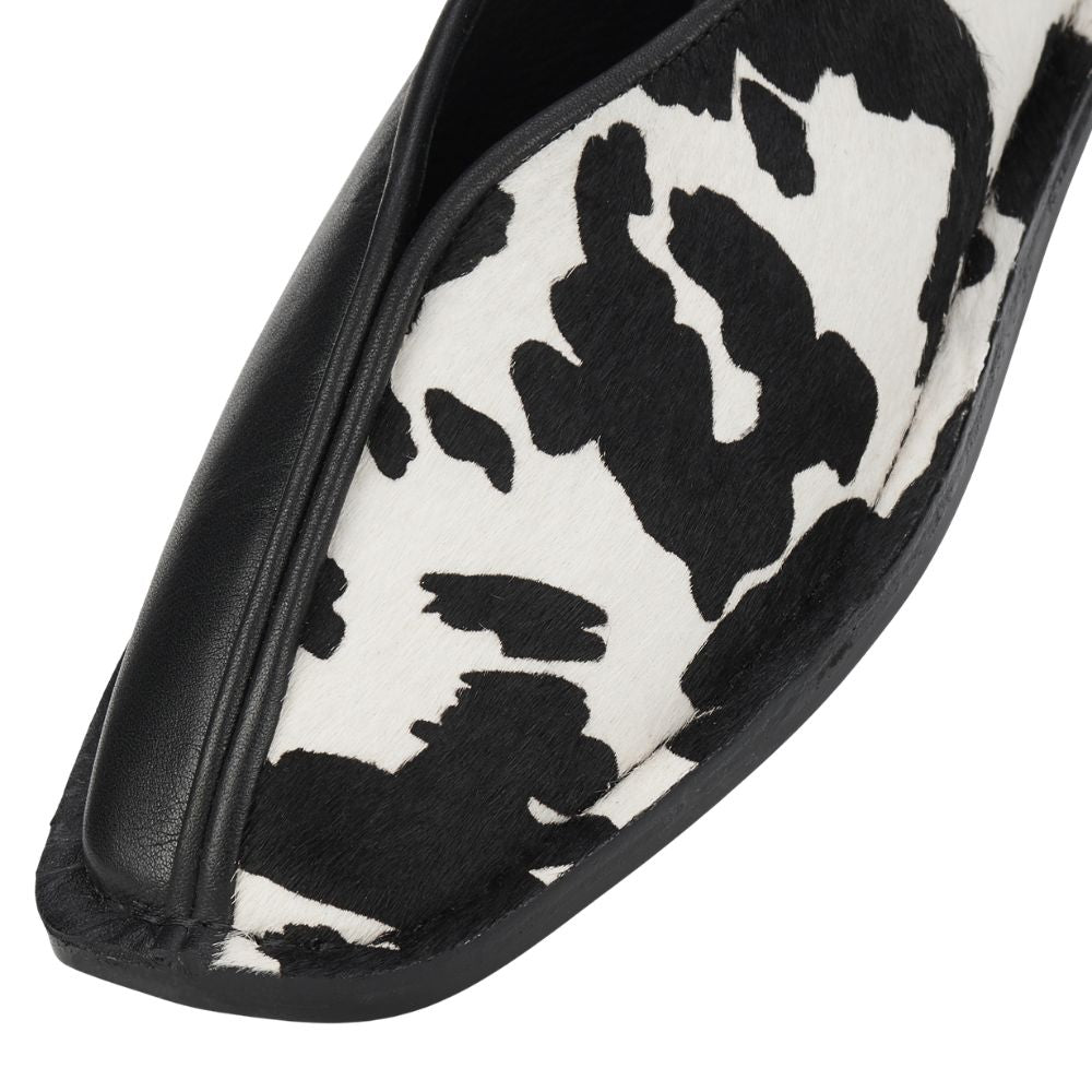 Black and white cow print flat shoe on a white background