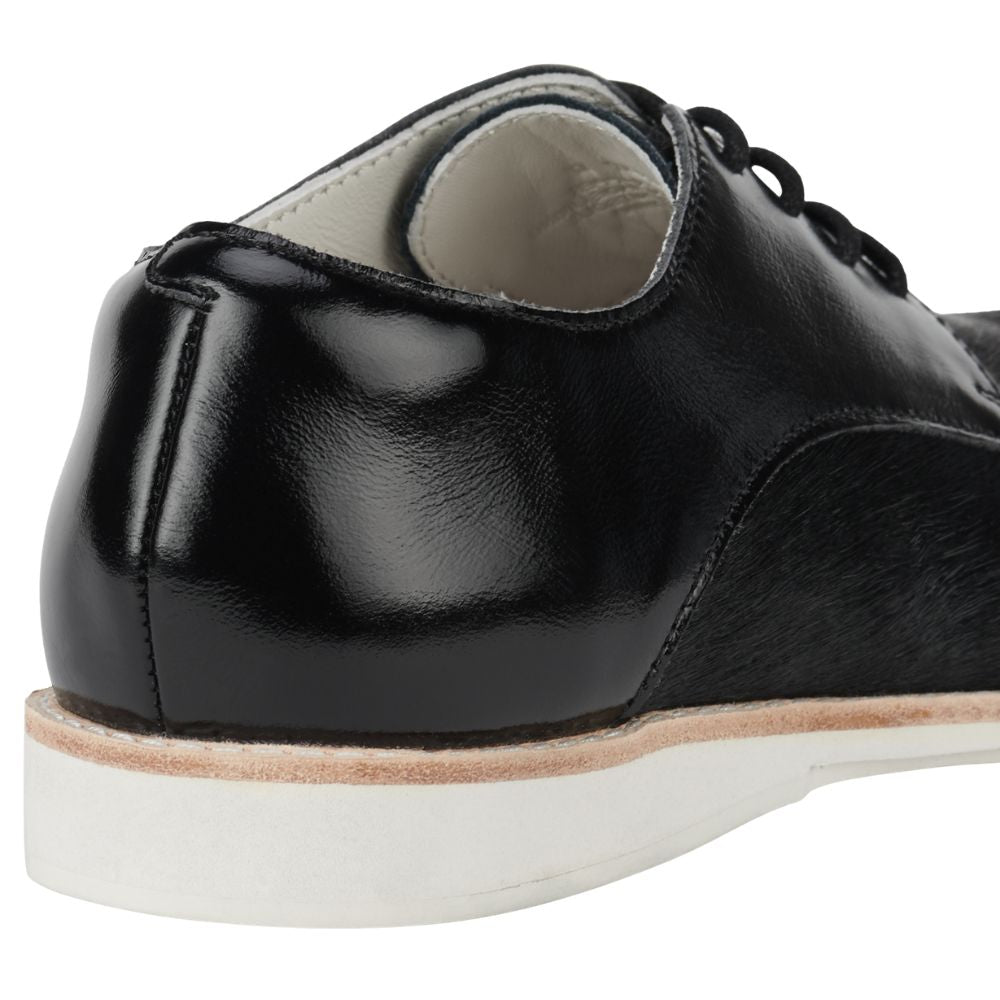 Back of black patent and pony leather shoe with black laces on a white background