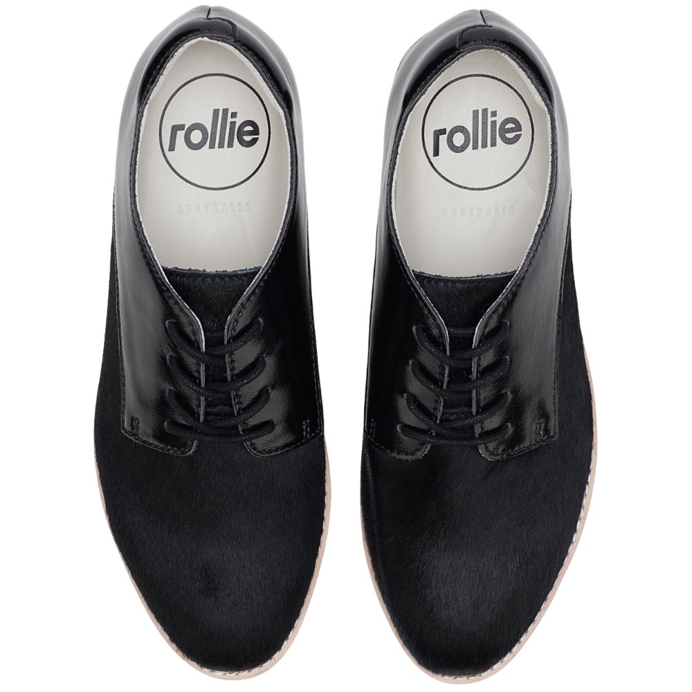 Pair of black patent and pony leather shoe with black laces on a white background