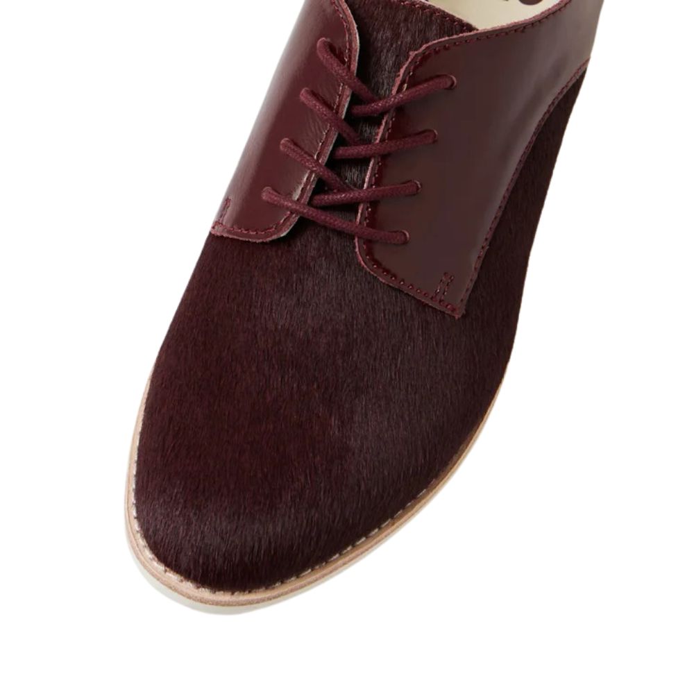 Cherry burgundy leather shoe with a fur texture upper on a white background