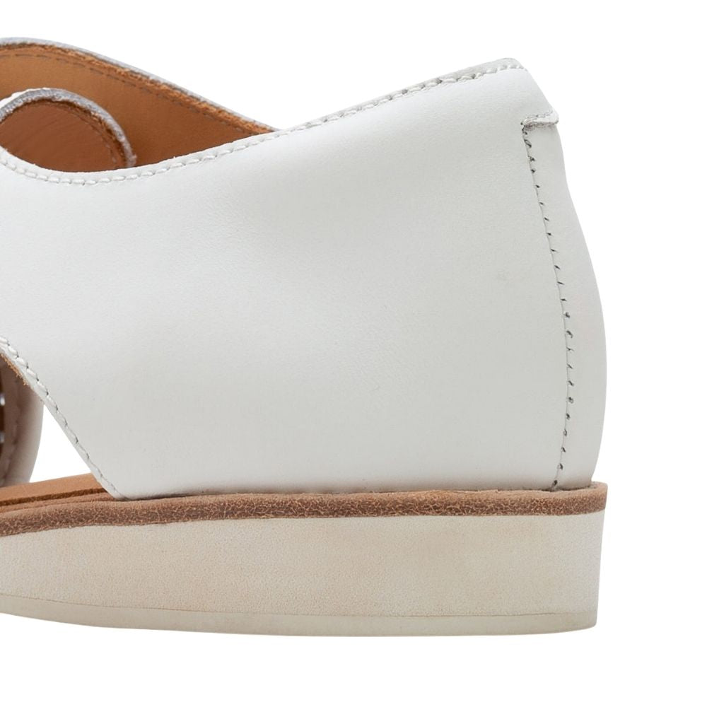 Close-up of the heel and side of a white leather shoe with a tan footbed and off-white sole on a white background.