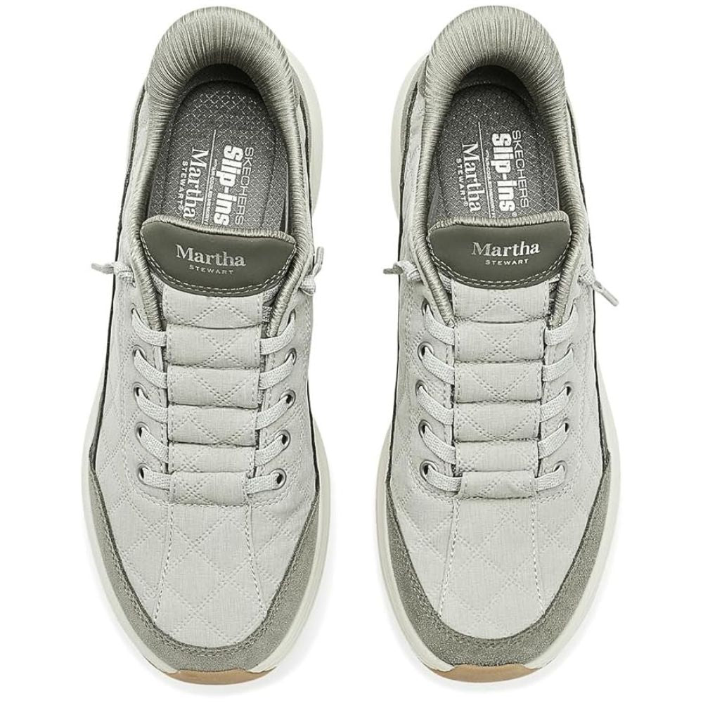 A pair of sage slip-on sneakers shown from a top-down view on a white background. The shoes feature a quilted texture, matching sage laces, a sage collar, and a sage tongue with the 'Martha Stewart' brand name.
