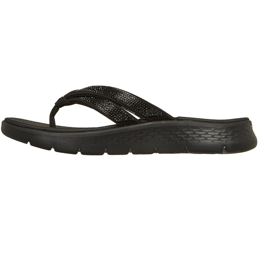 A single beige flip-flop sandal with metallic black rhinestone embellished straps, shown in a side profile on a white background. 