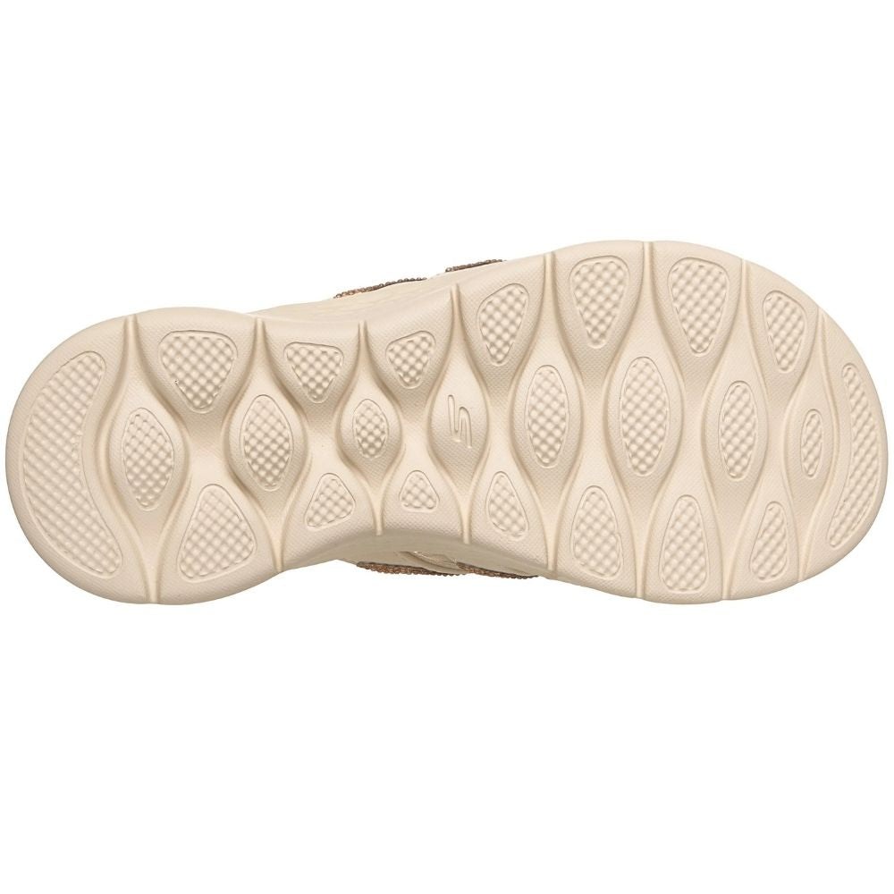 A close-up top-down view of a beige slip on sandal sole with textured, wavy tread patterns on a plain white background.