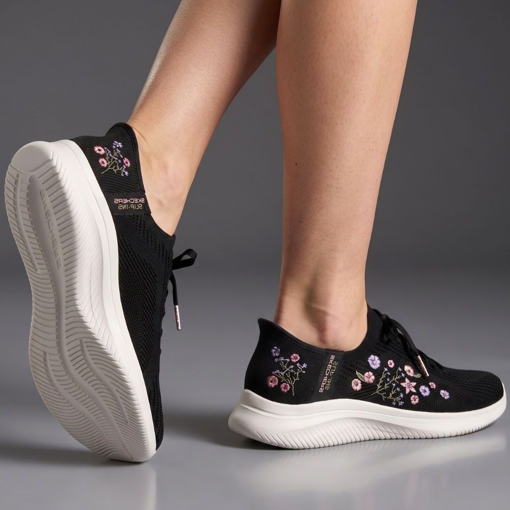 Black sneakers with floral embroidery on a gray background