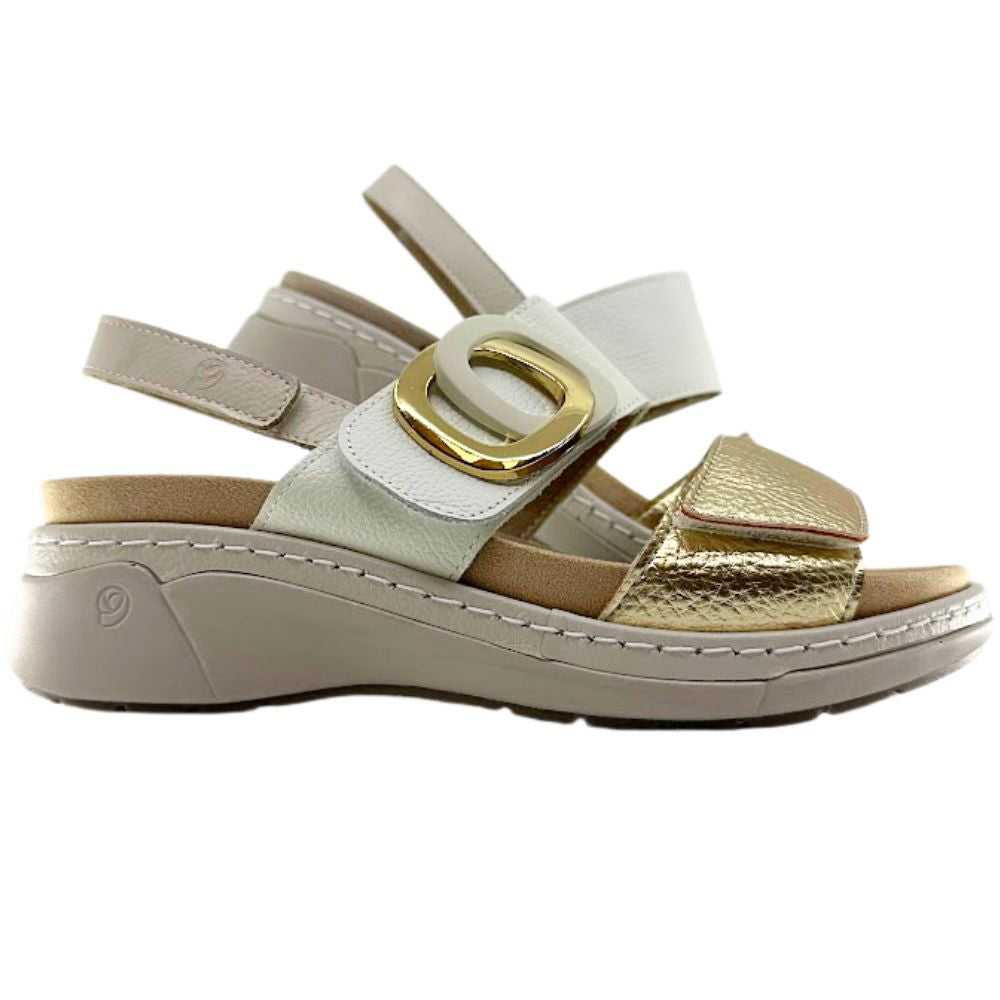 A women's platform wedge sandal featuring a light beige sole and straps, a metallic gold textured toe strap, and a large gold buckle on a white background.