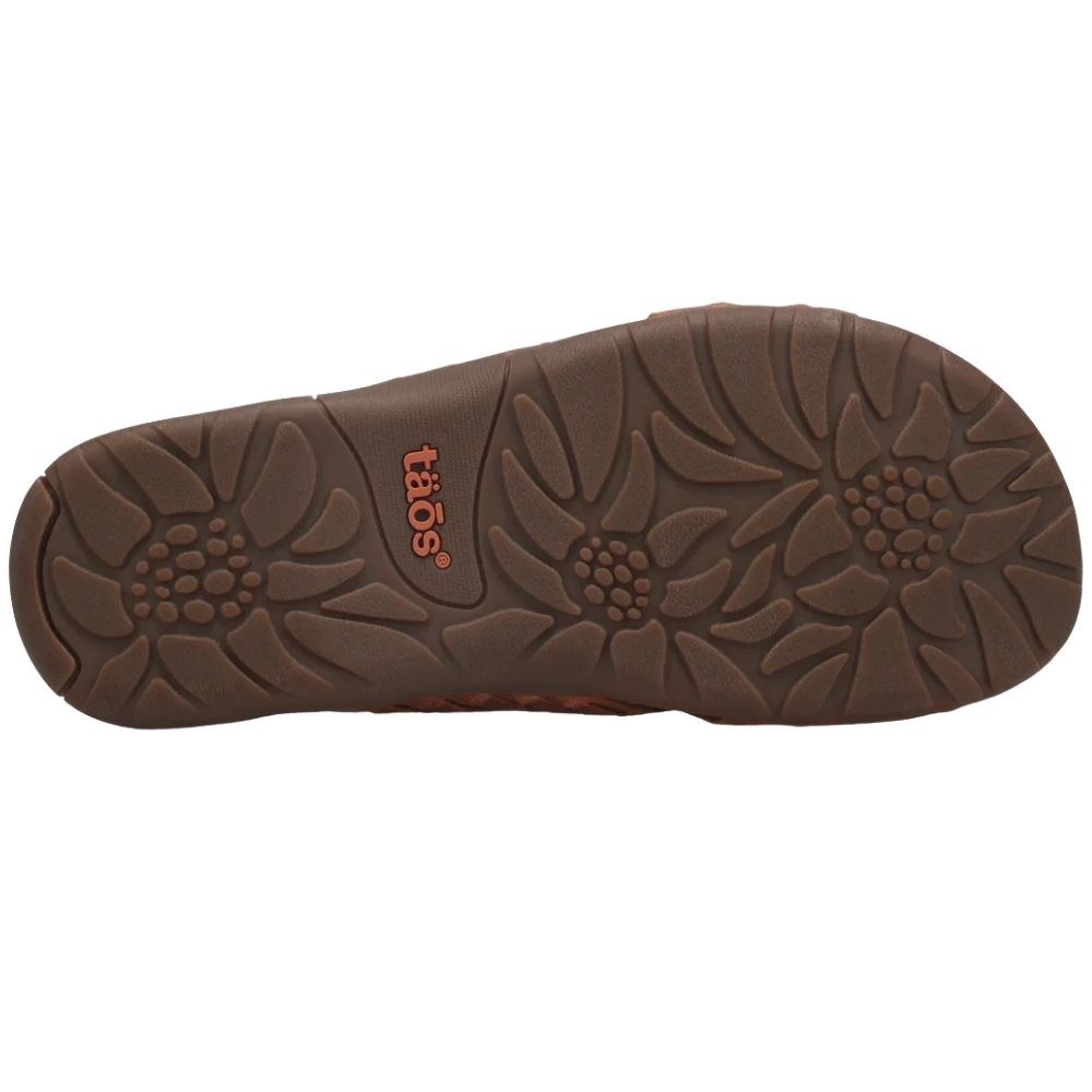 The brown textured outsole of a toas brand sandal, showing a floral tread pattern and the brand logo in orange-red.