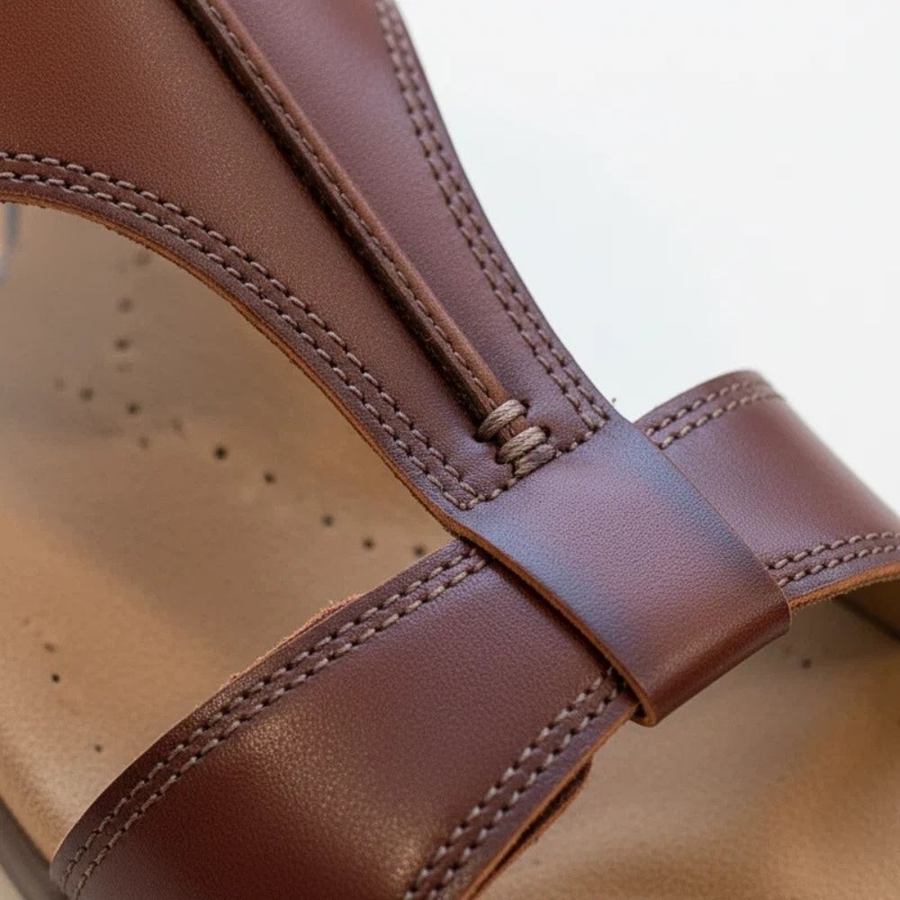 Close-up of a cognac sandal with leather strap and open toe design.