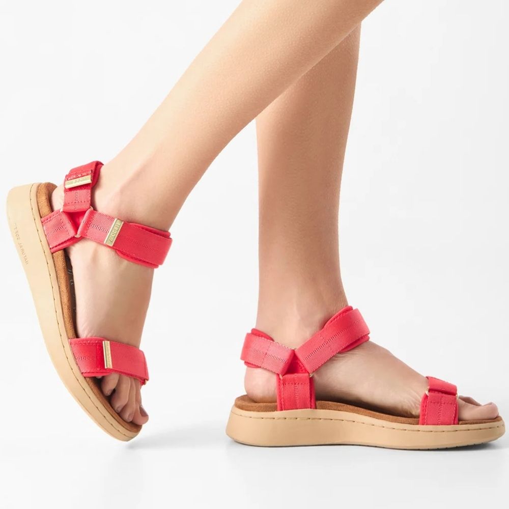 A pair of women's platform sandals in red with tan soles and small gold hardware, shown on a model's feet against a white studio background.