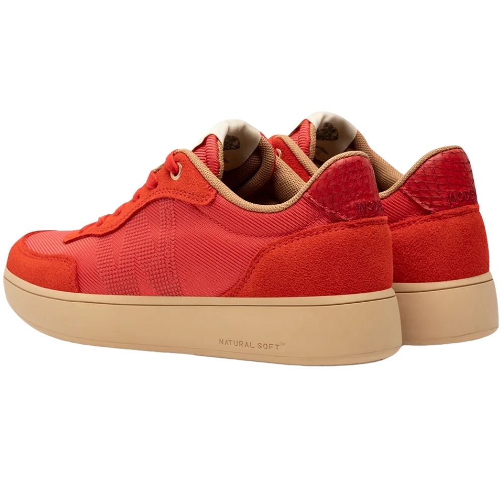 A pair of low-top platform sneakers in vibrant red, featuring textured mesh panels, suede overlays, matching red laces, and a thick beige sole with 'NATURAL SOFT' printed on the side.