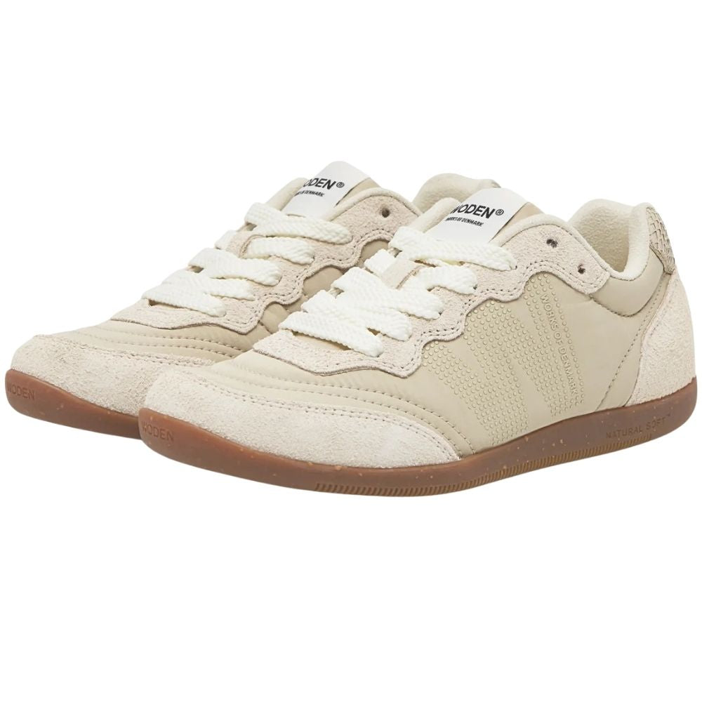 A pair of low-top sneakers in a light cream/beige colorway with a brown gum sole, shown on a plain white background.