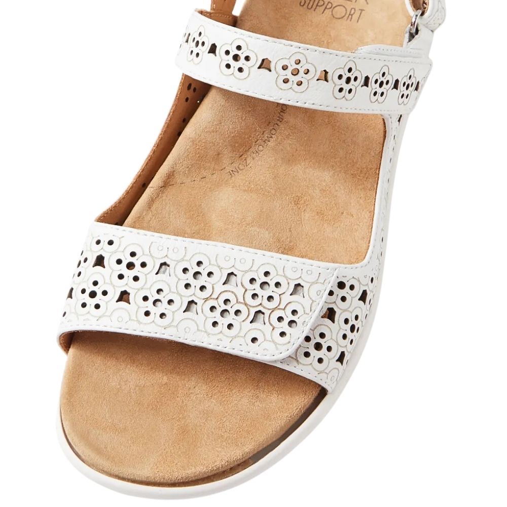 White open-toe wedge sandal with floral laser-cut straps and a tan footbed, shown on a white background.