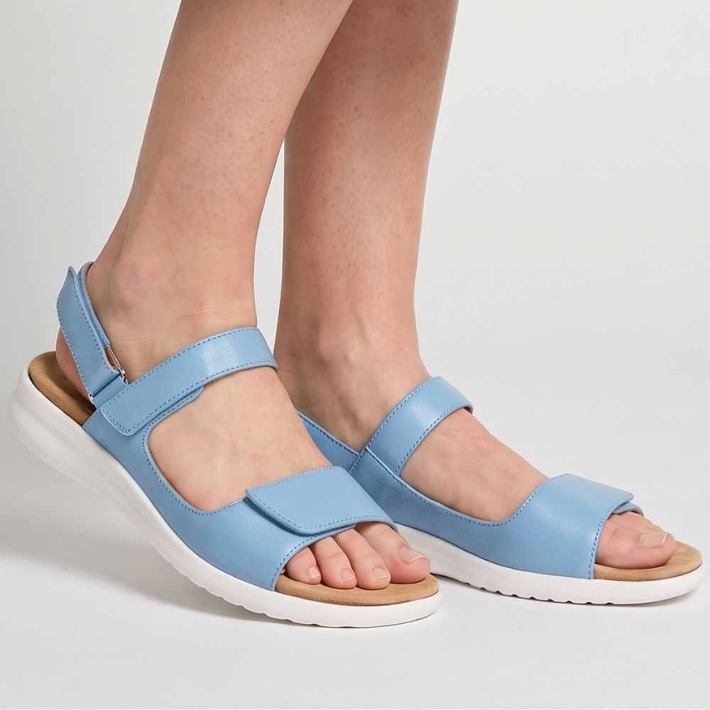 A pair of light blue leather ZIERA sandals with adjustable straps and thick white soles, shown on a model's feet against a light gray studio background.