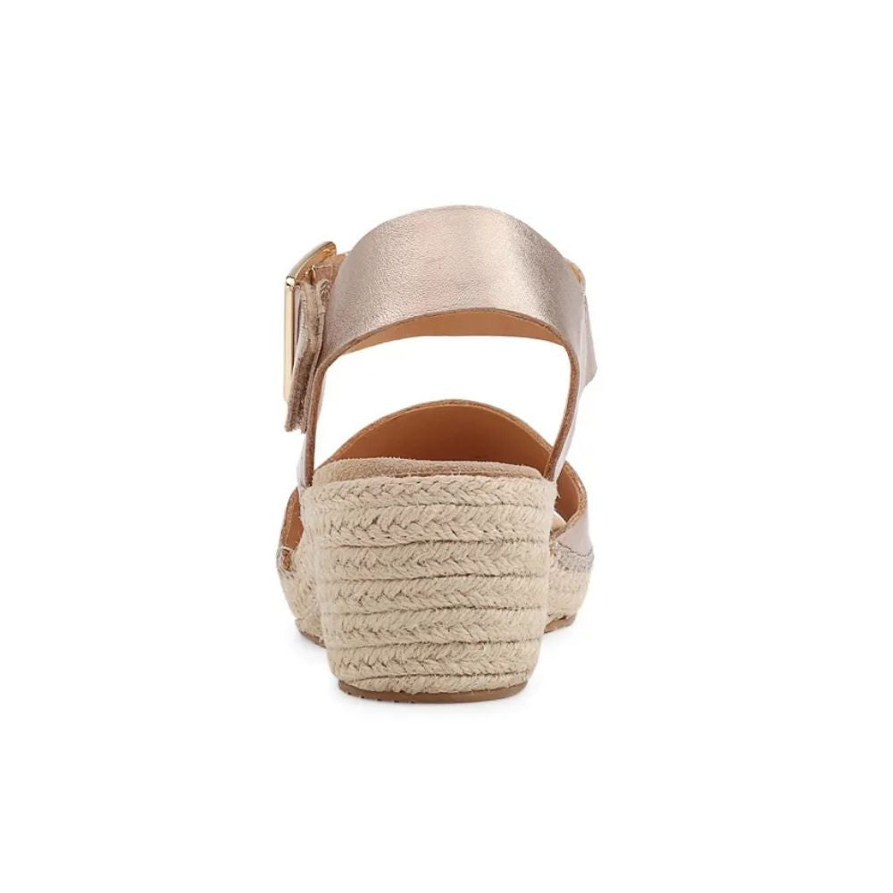 A single women's espadrille sandal shown from a rear three-quarter view, featuring a metallic champagne-gold ankle strap with a buckle and a natural beige braided jute platform heel, set against a plain white background.