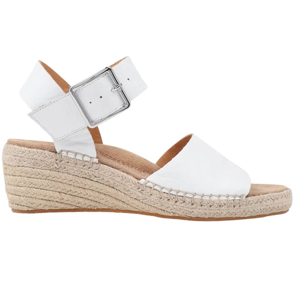 A white leather wedge espadrille sandal with a silver buckle ankle strap and a braided jute wedge heel, shown in a side profile on a white background.